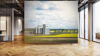 Field of rapeseed flowers, plant for cleaning and storage of agricultural products, flour, cereals and grains. Wall mural