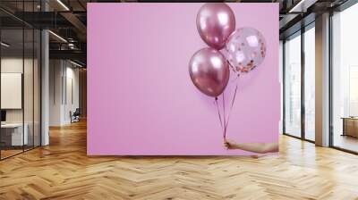 stylish birthday party or holidays with 3 bright balloons close up. Hand  holding three pink balloons isolated on  pink background with copy space for text. background for birthday greeting card  Wall mural