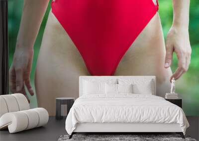 Close-up on a slim woman body in a red swimsuite. Wall mural