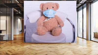 Teddy bear wears a protective medical mask, closeup. Wall mural