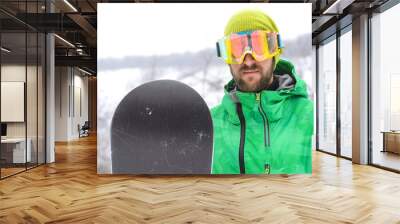 Young man standing in the snow of a snowboard and in a protectiv Wall mural