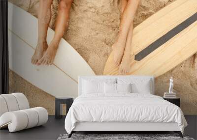 Beautiful long legs of two young girl in sexy bikini lycra on a sand beach after surfing with wooden surf white surfboard board at sunrise sunset. Vacation concept. Summer holidays. Tourism, sport. Wall mural