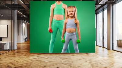 Children girls doing fitness exercises on green background together Wall mural