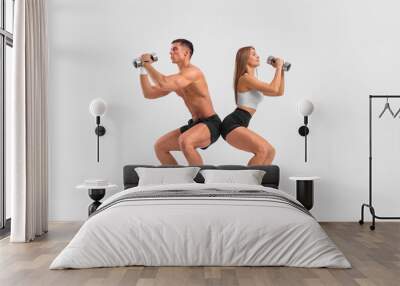 Fit couple at the gym isolated on white background with dumbbells. Fitness concept. Healthy life style. Wall mural