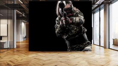 Heavily armed masked paintball soldier isolated on black background. Ad concept. Wall mural