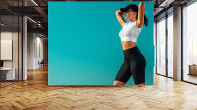 Individual sports and fitness recreation. Sporty and fit young woman athlete relaxed after yoga training on the sky background. The concept of a healthy lifestyle and sport. Wall mural