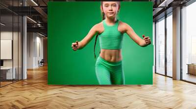 Kid girl doing fitness exercises on green background Wall mural