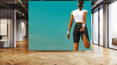 Sporty young woman and fit athlete runner warm up before taking a jogging on the sky background. Concept of a healthy lifestyle and sport. Woman in black and white sportswear running. Wall mural