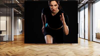 Sprinter and runner. Woman running on the black background. The concept of a healthy lifestyle and sport. Woman in sportswear. Wall mural