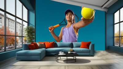 Tennis player. Beautiful girl teenager and athlete with racket in pink sporswear and hat on tennis court. Fashion and sport concept. Wall mural