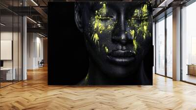 Woman with black body paint. Cheerful young african girl with art bodypaint. An amazing model with yellow makeup. Closeup face. Wall mural