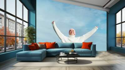 Portrait of happy young woman with cancer with arms up Wall mural