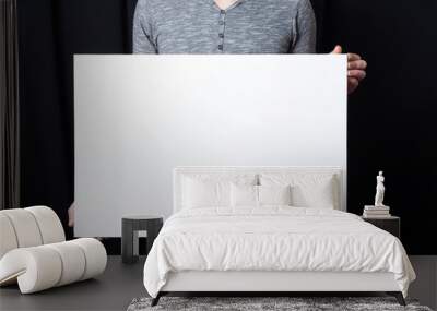 A man holds in his hands a white rectangular blank canvas Wall mural