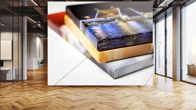 Photography canvas prints. Stack of colorful photos with gallery wrap on white wooden table. Stretched photo canvases, lateral side, closeup Wall mural