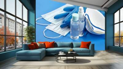 Protection against coronavirus, sanitizer, respirator n95, disposable surgical face masks and rubber gloves on blue background Wall mural