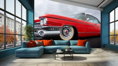 Side view of a classic american car from the fifties. Low angle view showing red paint and chrome fender and grill. Wall mural