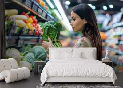 A beautiful young woman chooses vegetables at a supermarket.  Shallow depth of field Wall mural