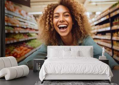 A cheerful and smiling woman customer pushing a shopping cart filled with fresh groceries down the supermarket aisle, the joy of products shopping. Wall mural