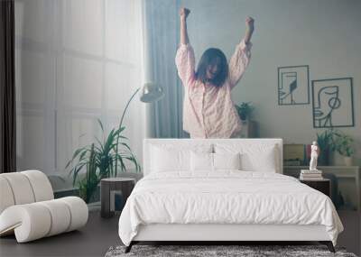 Happy woman dancing on sofa in living room Wall mural