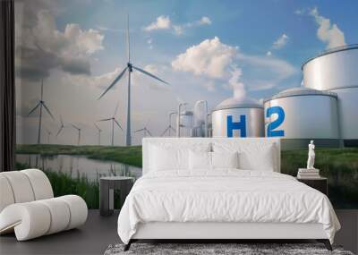 Hydrogen storage tanks marked with H2 and wind turbines stand in a green, eco-friendly landscape with a pond, under a bright sky Wall mural