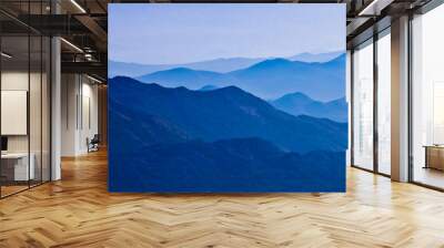  with blue misty mysterious mountains in the distance and an orange pastel sky. Distant blue mountains. Wall mural