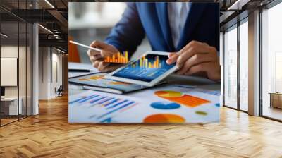 Businessman analyzing sales data on tablet with economic growth chart for strategic planning Wall mural