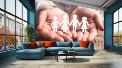 Family security and support symbolized by hands holding paper cutout family in photography shot Wall mural