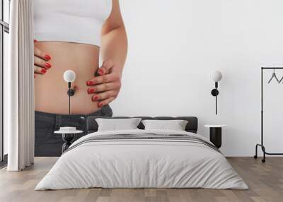 a young woman massages her stomach with two hands. On white background. With place for a copyspace Wall mural