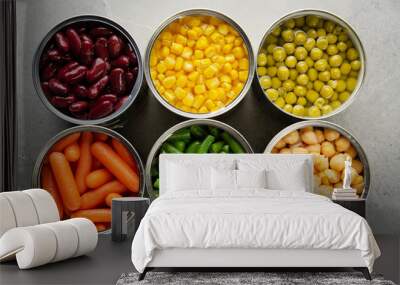 Flat lay view at canned carrots, chickpeas, kidney beans, green beans, peas and corn in opened tin cans on kitchen table. Non-perishable foods background Wall mural