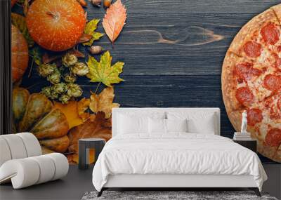 autumn background with pumpkins, autumn leaves, hops and oak acorns lying on a black wooden background Wall mural