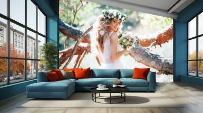 beautiful bride in nature in a coniferous forest in a wreath on her head and a luxurious wedding dress Wall mural