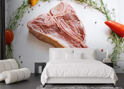 raw t-bone steak in the center of a Christmas wreath of rosemary thyme cherry tomatoes and bell peppers on a white marble surface. christmas dinner concept Wall mural