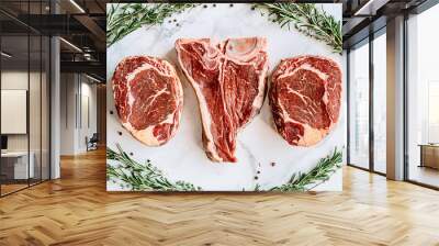 three delicious steaks ready to grill on a white marble surface Wall mural