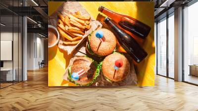 three fresh and juicy burgers with American flag-style fireworks inserted into them. bbq concept picnic to celebrate independence day Wall mural