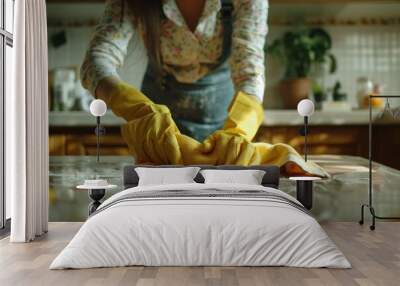 Cheerful housewife in yellow gloves wiping down a table with a cloth in a close up shot Wall mural