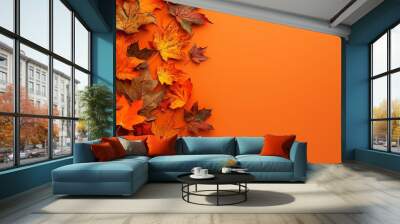 Top view of vibrant autumn leaves on orange background with ample space for adding text overlay Wall mural