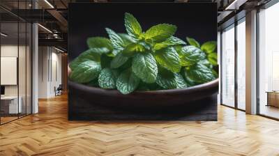 A bowl of fresh mint leaves sits on a dark wooden surface Wall mural