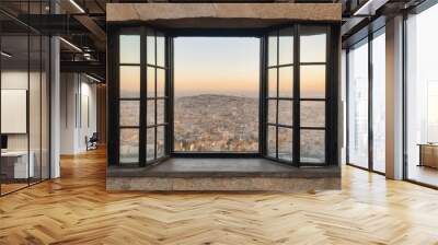 A large window offers a breathtaking view of a city from a stone building Wall mural