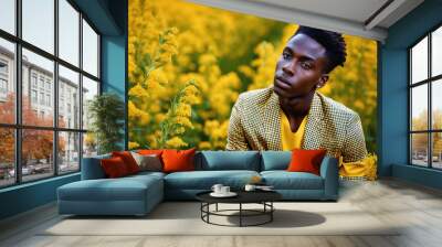 A man in a yellow checkered jacket stands in a field of yellow wildflowers Wall mural