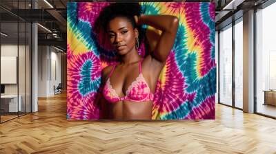 A woman wearing a pink bikini top and pink panties, posing in front of a colorful background with tie-dye patterns. Wall mural