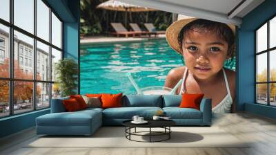 A young girl is sitting in a pool with a straw in a glass of liquid Wall mural