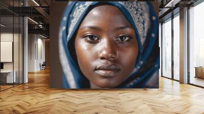 A young woman wearing a blue headscarf looks directly at the camera Wall mural