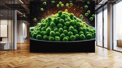 Green peas are scattered across a black background, with a pile of peas on a green plate in the foreground Wall mural