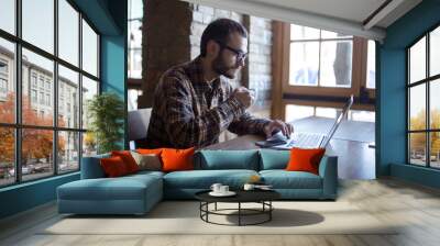 young man drinking coffee on the street while using tablet computer Wall mural