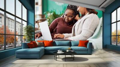 Best friends know the best fashion blogs. Shot of two young women using a laptop on the sofa at home. Wall mural