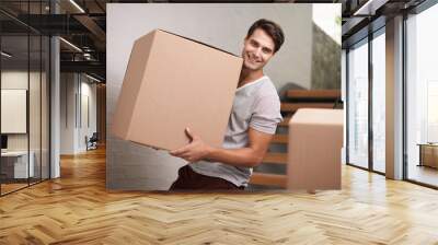 Cant wait to get to my new place. A happy young man moving packed cardboard boxes in his home. Wall mural