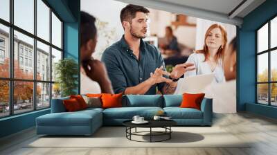 Setting out some clear objectives. Shot of a young businessman having a meeting with his colleagues in an office. Wall mural