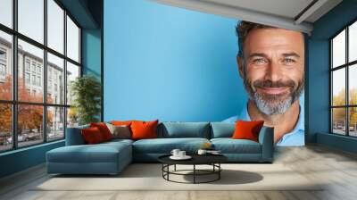  A bearded man, dressed in a blue shirt, smiles at the camera Wall mural