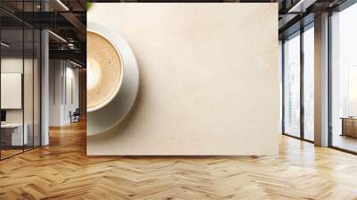  A cappuccino in a cup on a beige background, next to a green, leafy plant in a saucer Wall mural