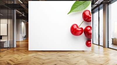  A few cherries atop a pristine white surface, accompanied by a lush green leafy plant Wall mural